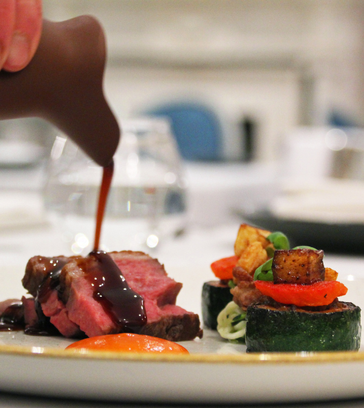 Medium rare beef with roast vegetables having gravy poured on top of it